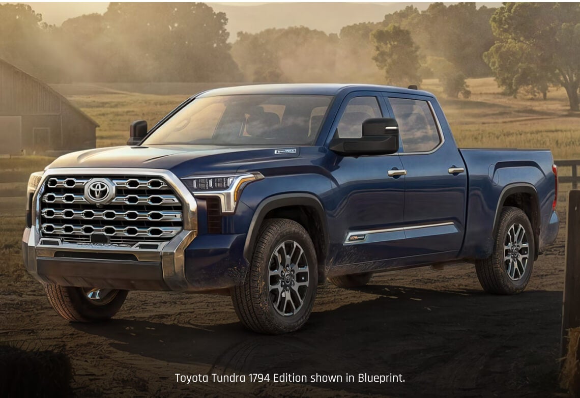 Front three-quarter view of a Toyota Tundra 1794 Edition in Blue parked on a dirt ranch path.